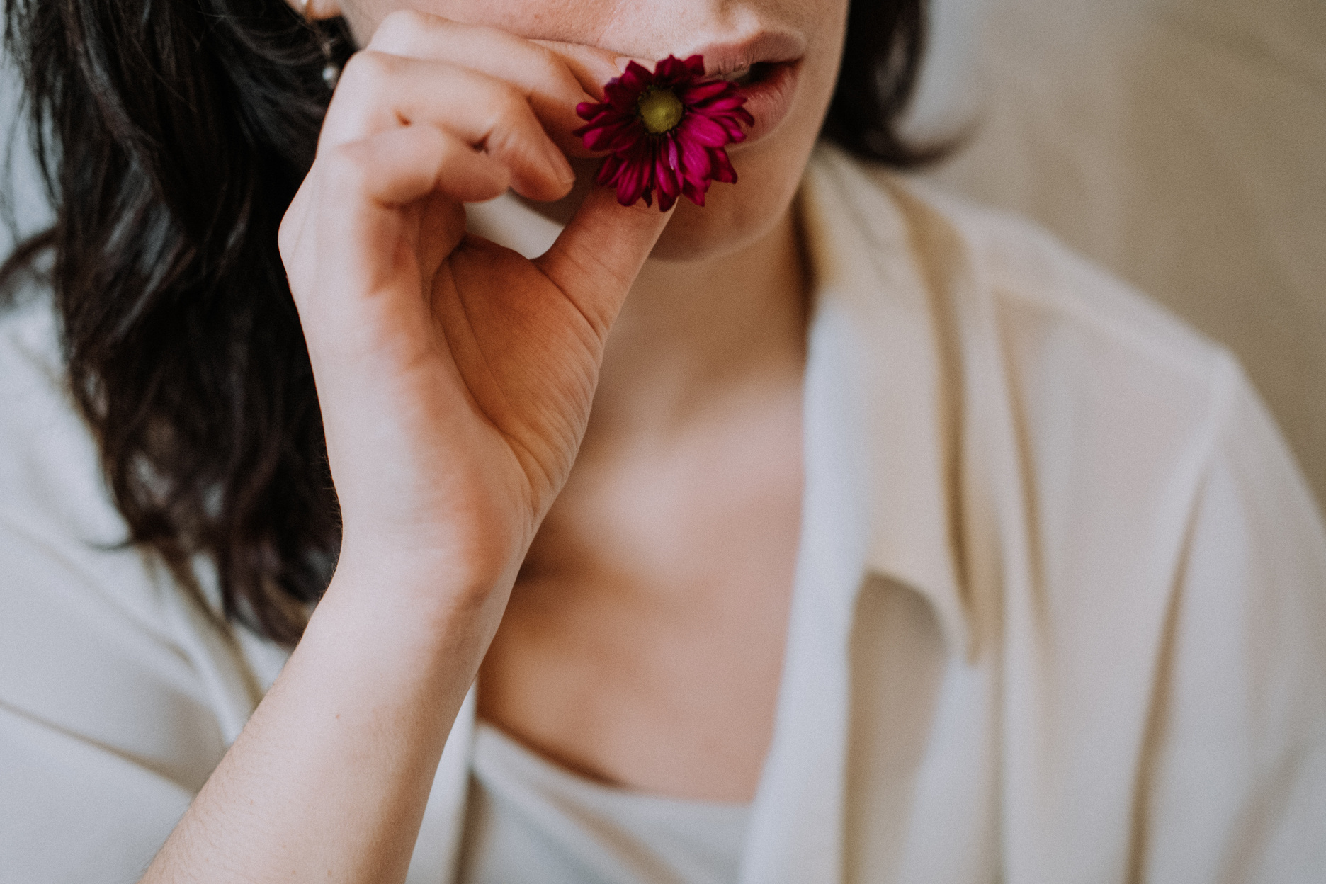 Woman putting blooming flower in mouth